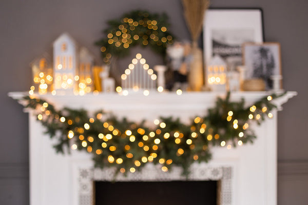 A fully decorated holiday mantel featuring a hefty Christmas garland and bokeh lights | Christmas World