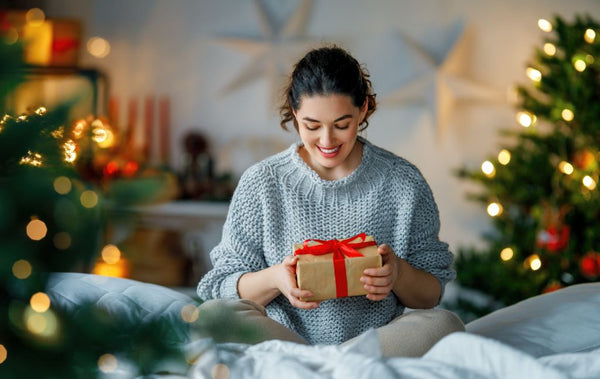 A woman holds a perfectly wrapped gift on Christmas morning | Christmas World