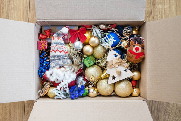 An open cardboard box full of loose Christmas ornaments. | Christmas World