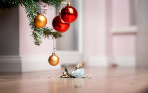 A shattered Christmas ornament on the ground beside a Christmas tree  | Christmas World