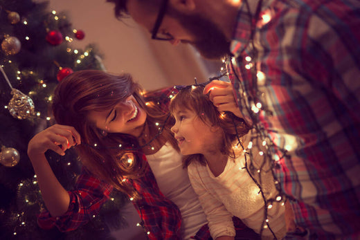 A mother and her small child smile as they hang Christmas lights indoors    | Christmas World