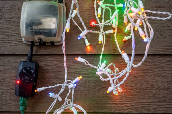 A strand of colored Christmas lights beside an outdoor Christmas lights timer. | Christmas World